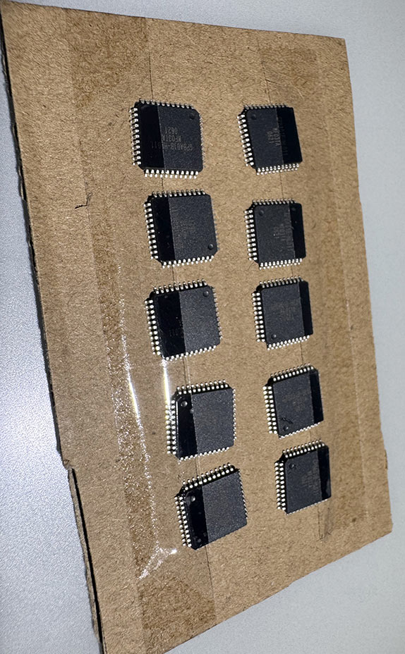 Ten TQFP-44 chips taped to a piece of cardboard