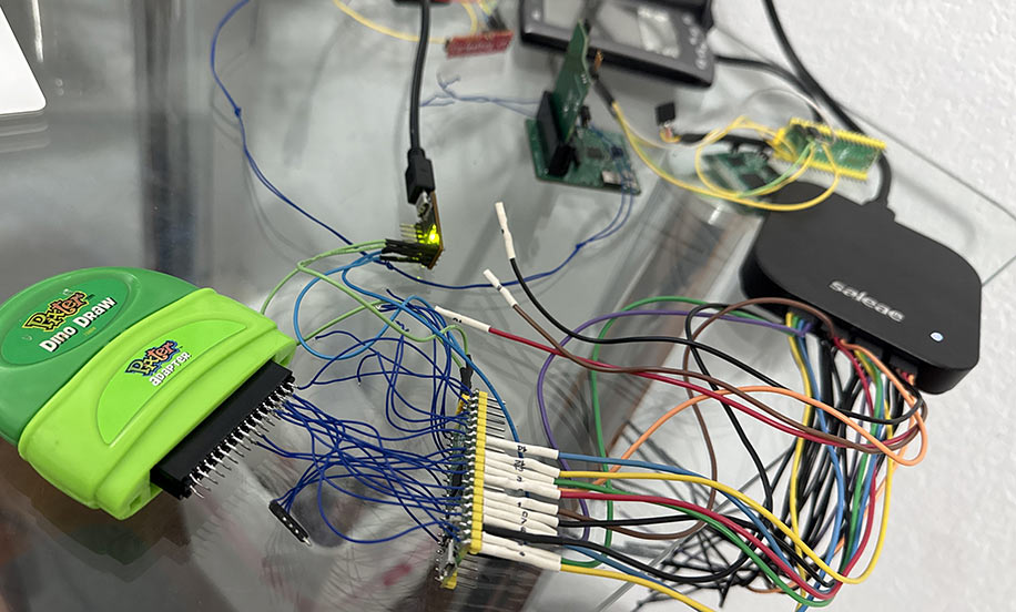 A logic analizer and a Pi Pico 2 connected by many wires to a Pixter Color cart in a connector